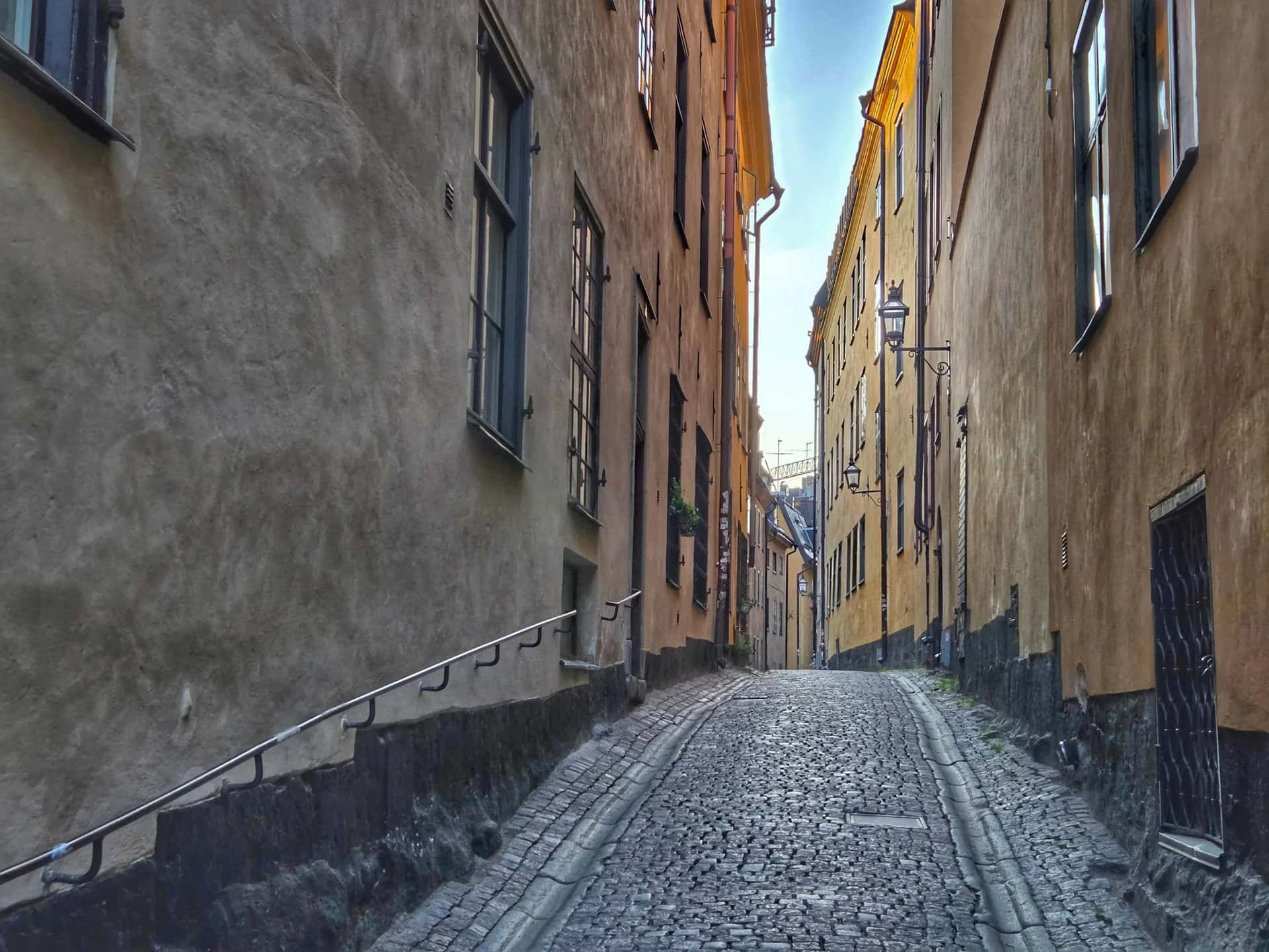 Smal, uppförslutande kullerstensgränd mellan gamla husväggar. Stadsvandring Gamla Stan