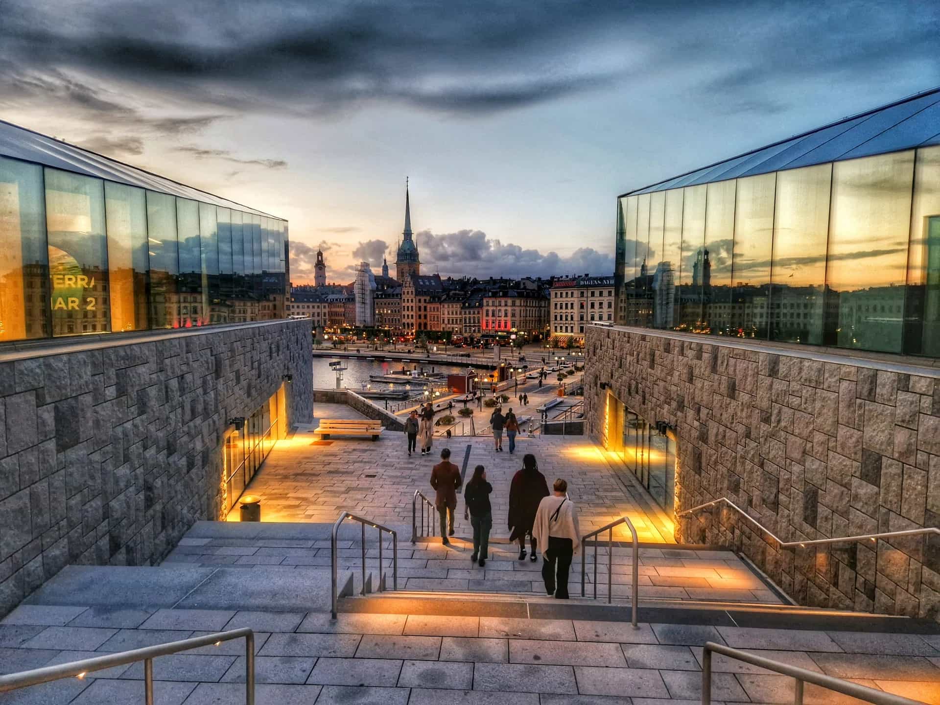 Stadsvandringar Stockholm: Kvällsutsikt över trappor, moderna byggnader, vatten och gamla hus med kyrkspira
