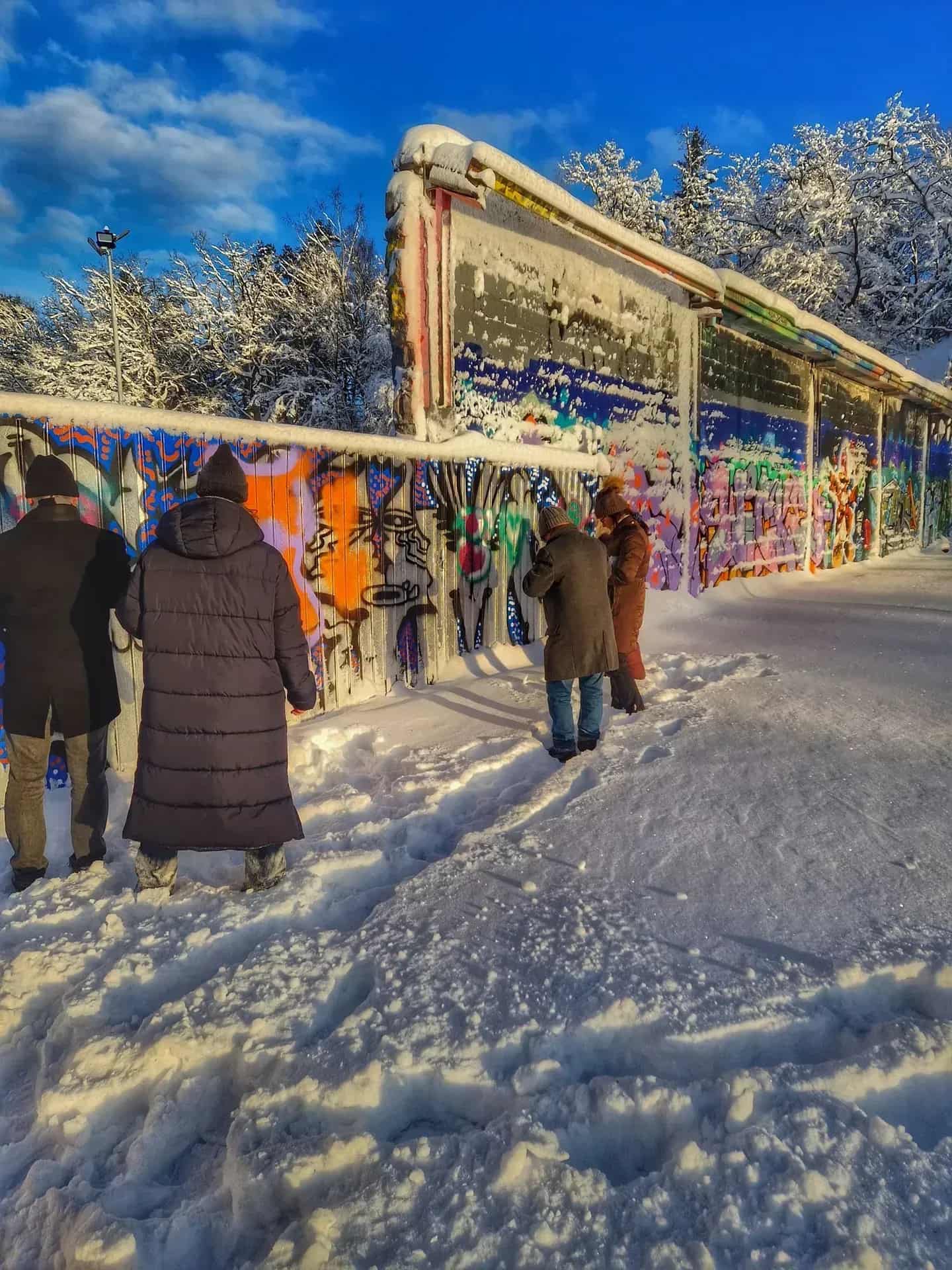 Four people in front of a graffiti-painted wall in a snowy landscape