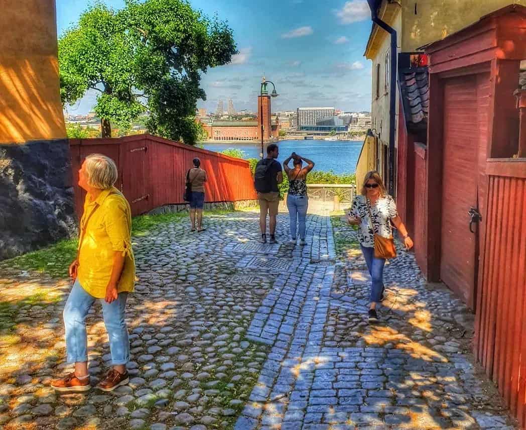 Street with cobblestones and people. Water and buildings in the background