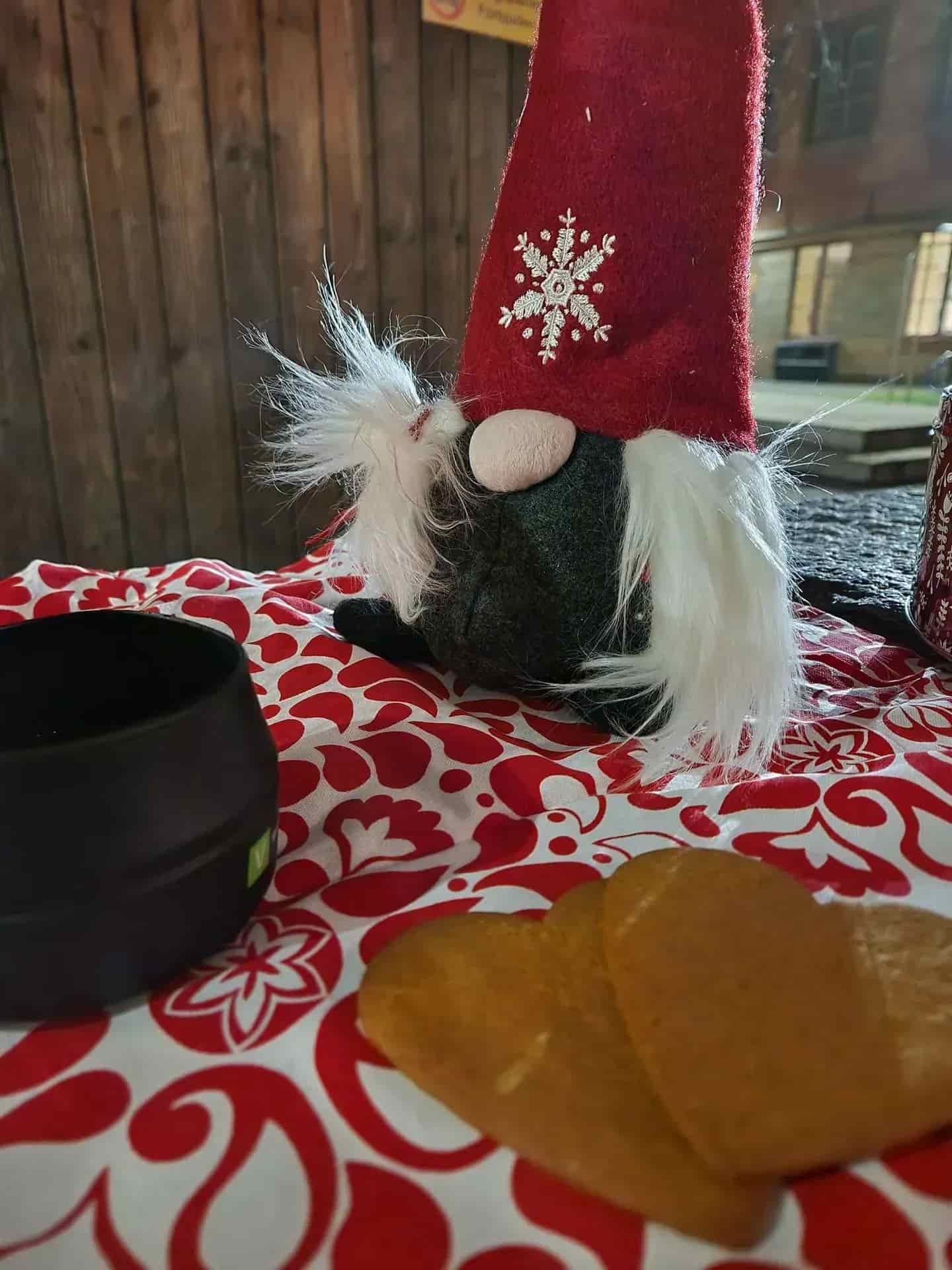 Christmas decoration: gnome with red hat, white beard, gingerbread cookies and black mug
