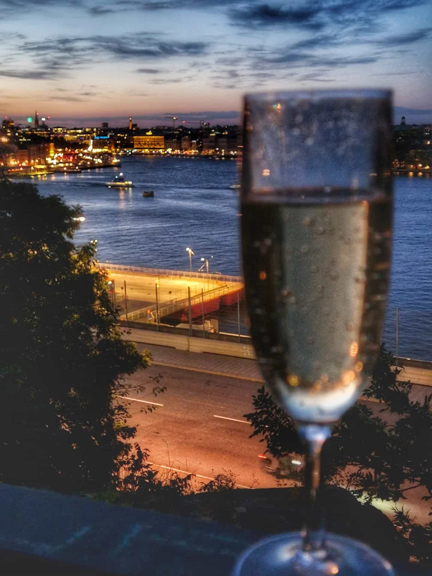 Stadsvandring Södermalm: Champagneglas framför upplyst stad och vatten vid skymning