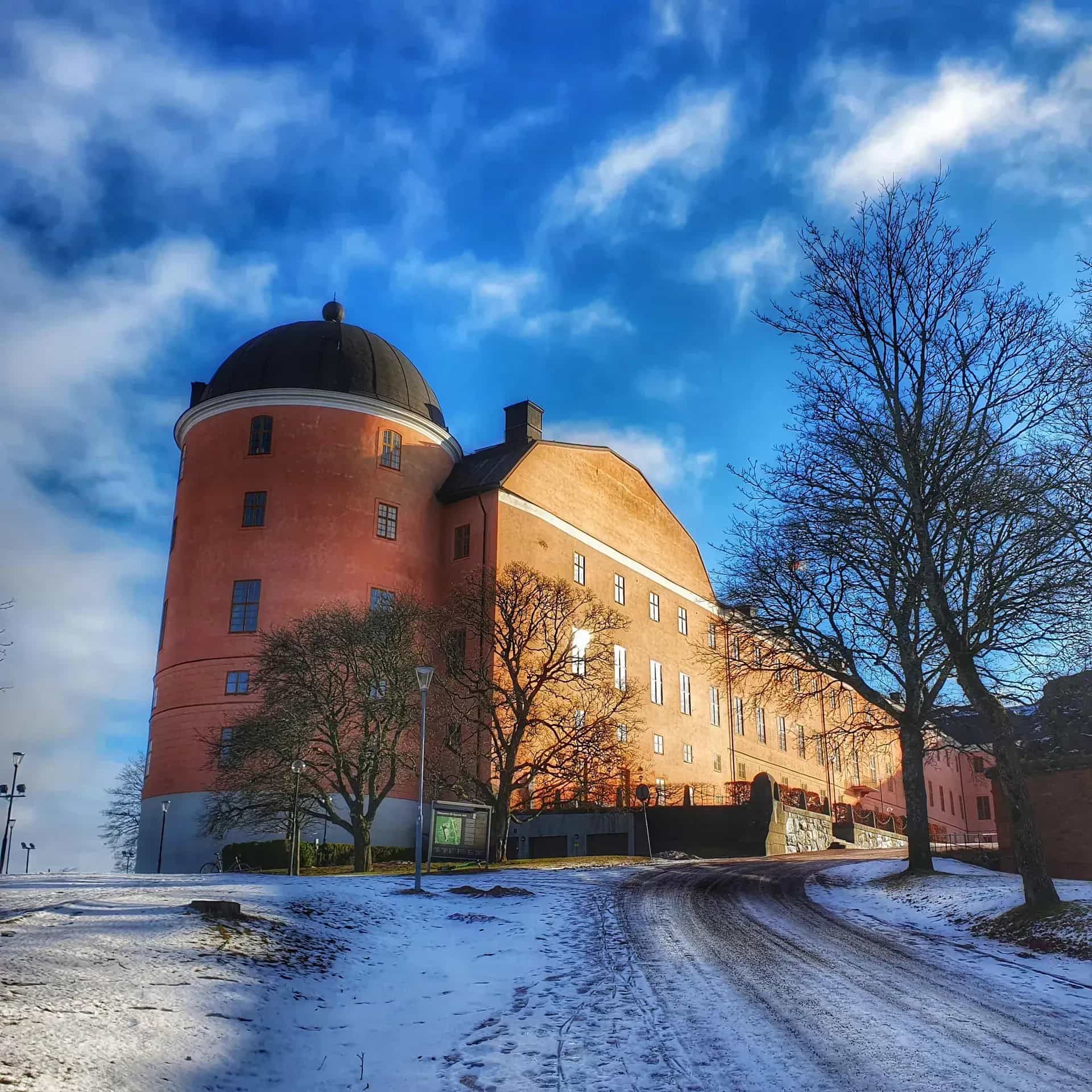 Uppsala slott i vinterlandskap under blå himmel. Snö på marken