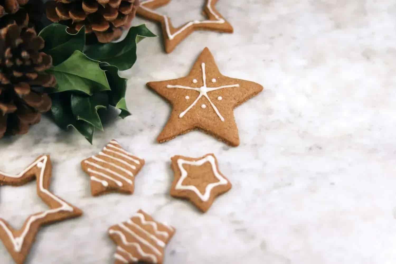 Gingerbread cookies, star-shaped, with icing. Pine cones and green leaves. Marble base